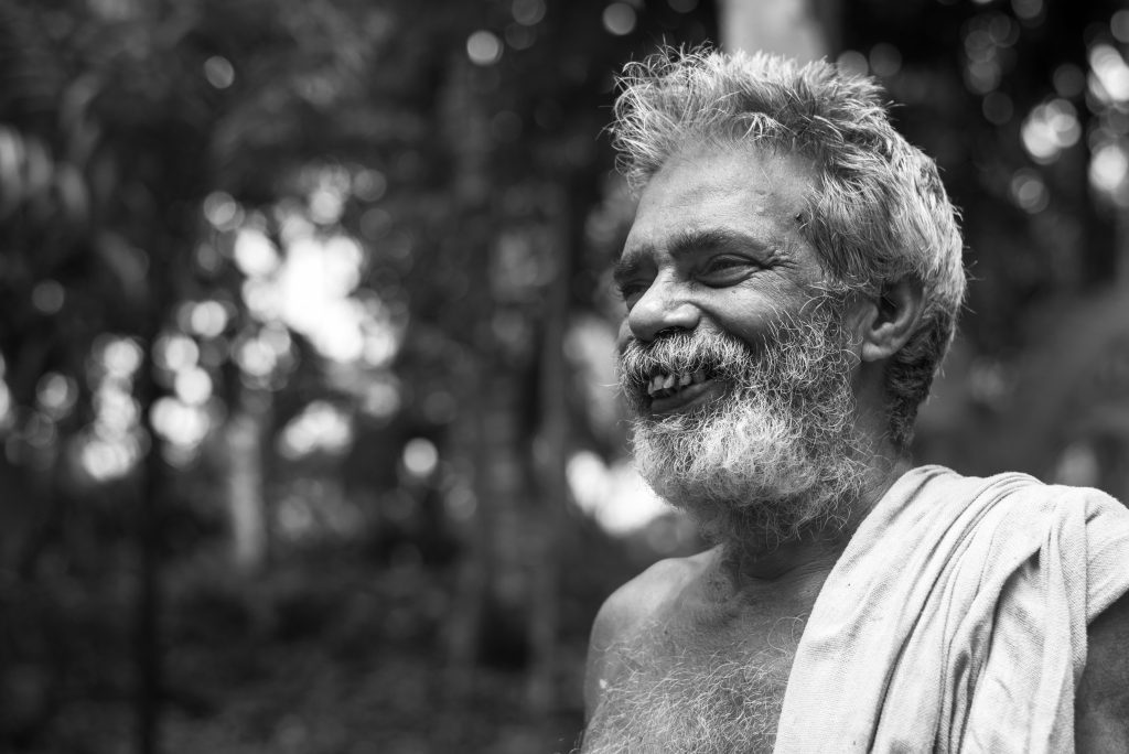 Black and white portrait of a smiling senior man in Vaikom, Kerala.
